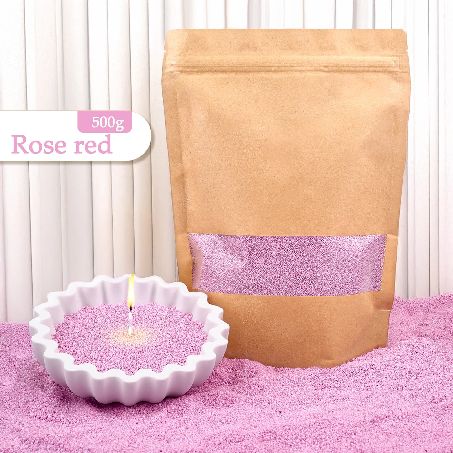 Nutshell rose red colored candle sand 500g in brown resealable bag with lit candle in white ceramic holder