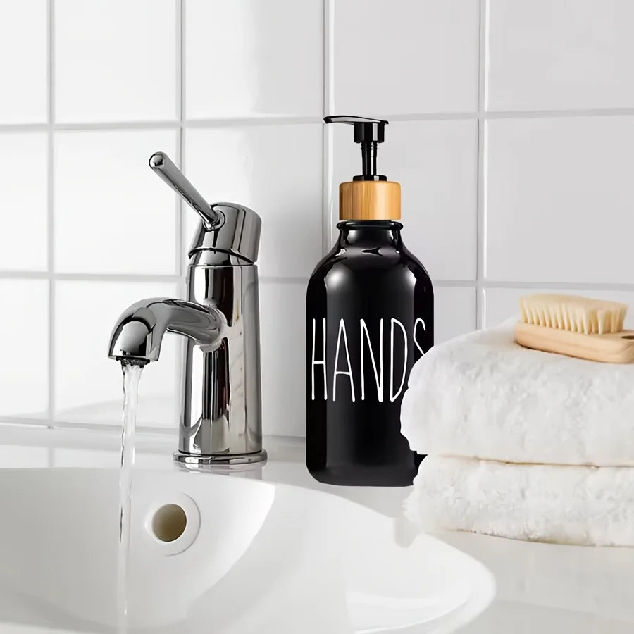 Nutshell countertop soap dispenser set with black pump bottle and bamboo lid next to running faucet and white towels
