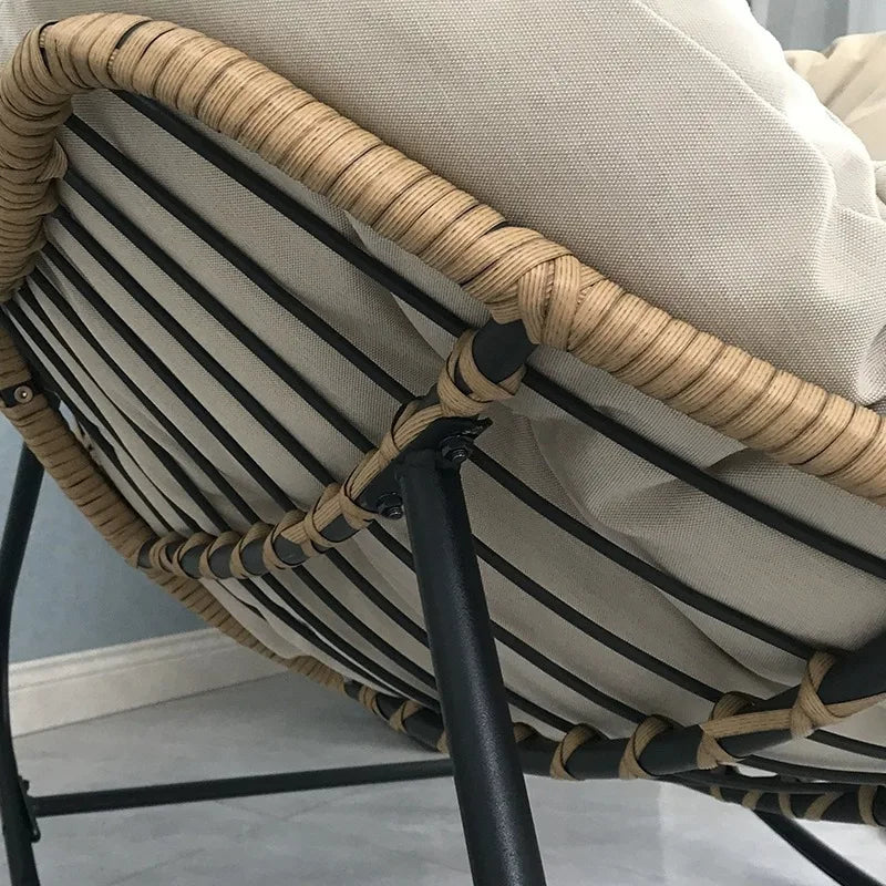 Nutshell lazy leisure rocking chair with cushion showing rattan wrapped frame black metal legs and beige cushion
