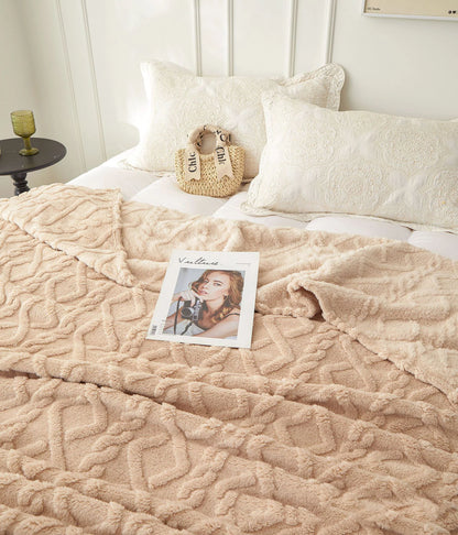 Nutshell warm sofa throw blanket in beige plush geometric texture draped on bed with pillows and magazine
