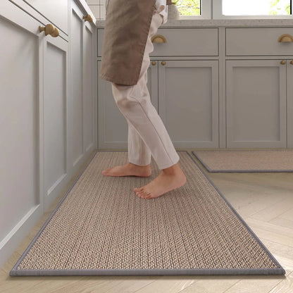 Nutshell washable non-slip kitchen rug runner in tan woven texture under barefoot person by gray cabinets