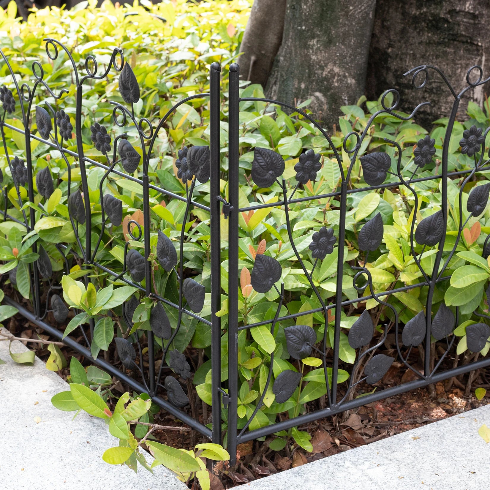 Nutshell black metal decorative garden fence panels with leaf and flower design around green garden plants