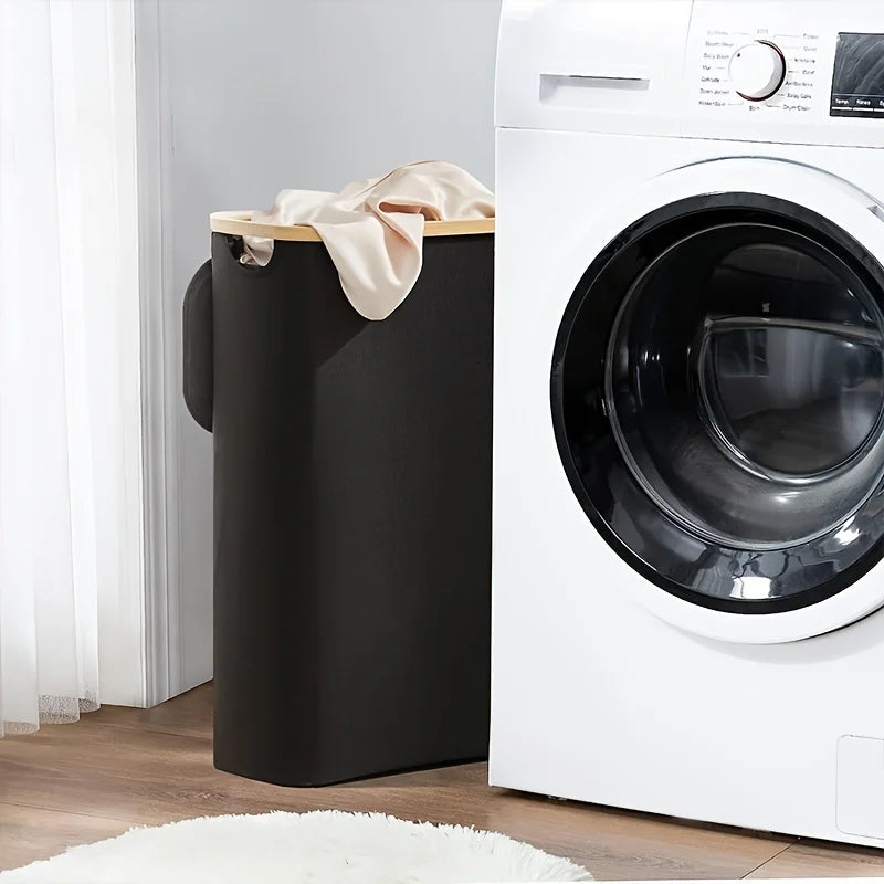 Nutshell collapsible bamboo clothes hamper in dark slim design with beige rim and handles next to washer