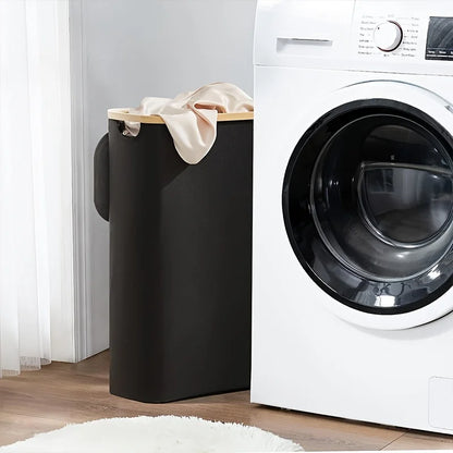 Nutshell collapsible bamboo clothes hamper in dark slim design with beige rim and handles next to washer