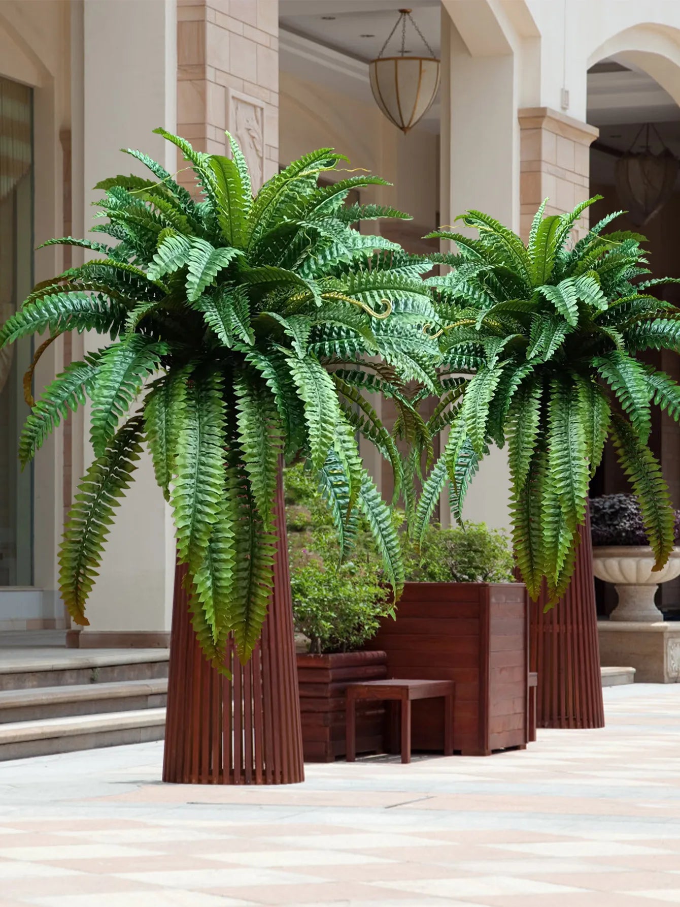 Nutshell artificial fern hanging plant with lush cascading fronds in tall wooden planters at hotel lobby