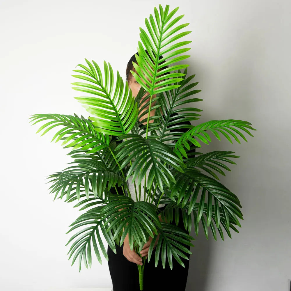 Person holding Large Artificial Palm Tree Monstera Tree Branch bundle of green faux palm fronds for home decor