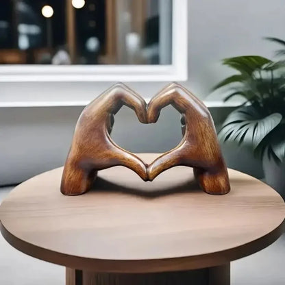 Heart-shaped resin sculpture decor depicting two hands forming a heart on a wooden table