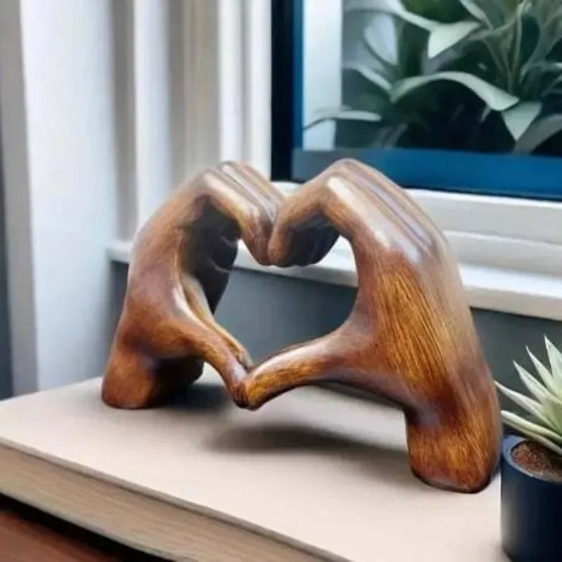 Heart-shaped resin sculpture decor featuring two hands forming a love symbol on a shelf