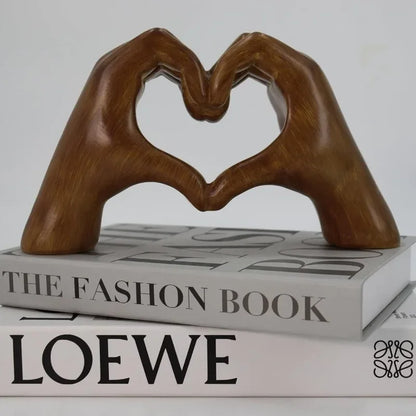 Heart-shaped resin sculpture decor featuring two hands forming a heart on stacked books