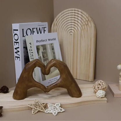 Heart-shaped resin sculpture decor with wooden hands forming a heart, styled in modern home decor setting