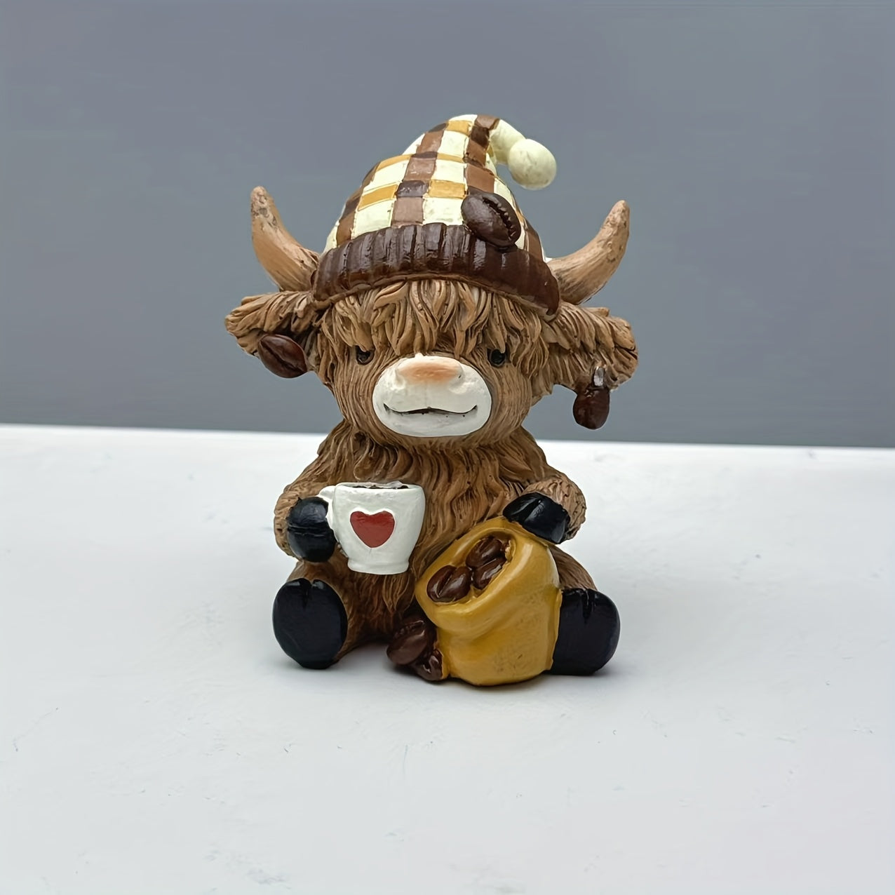 Adorable highland cow coffee decor figurines holding a mug and bag for cozy home accents