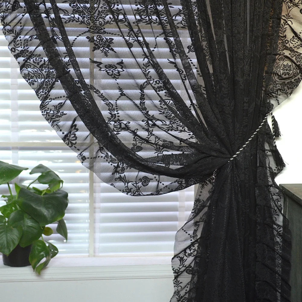 Black floral sheer curtain tied back at a sunlit window with blinds and plant vintage voile ruffle lace drapes