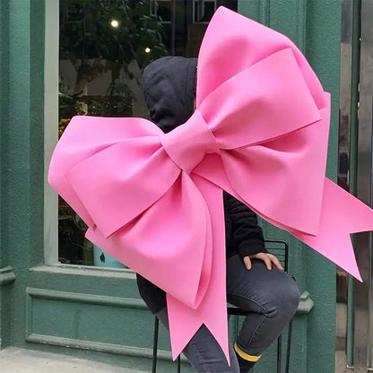 Large red bow displayed in a store with a person wearing a black hoodie in the background