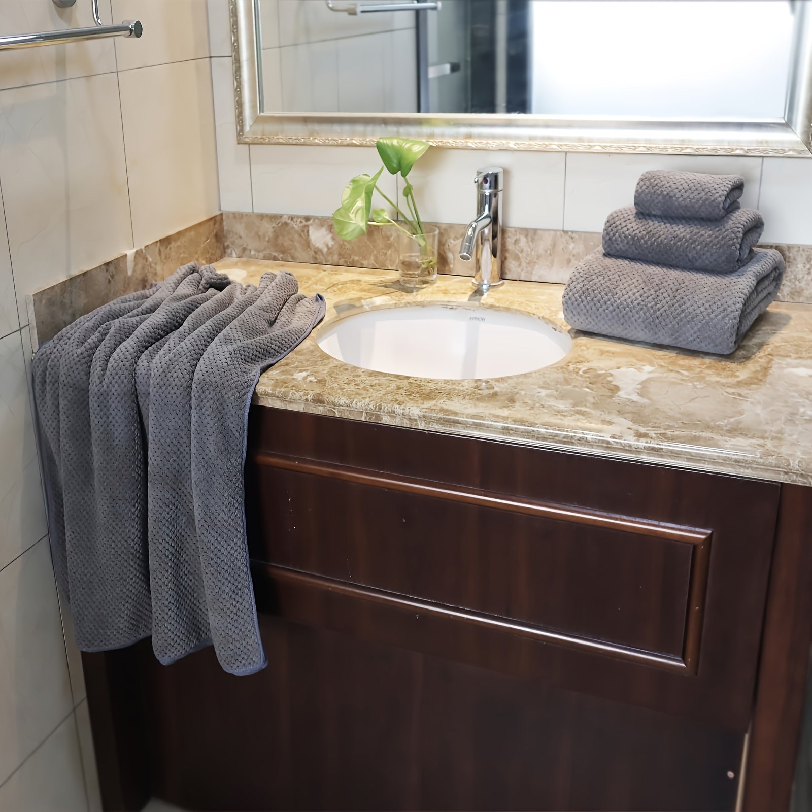 Nutshell luxury bath towel set in gray neatly arranged on a bathroom countertop with a sink