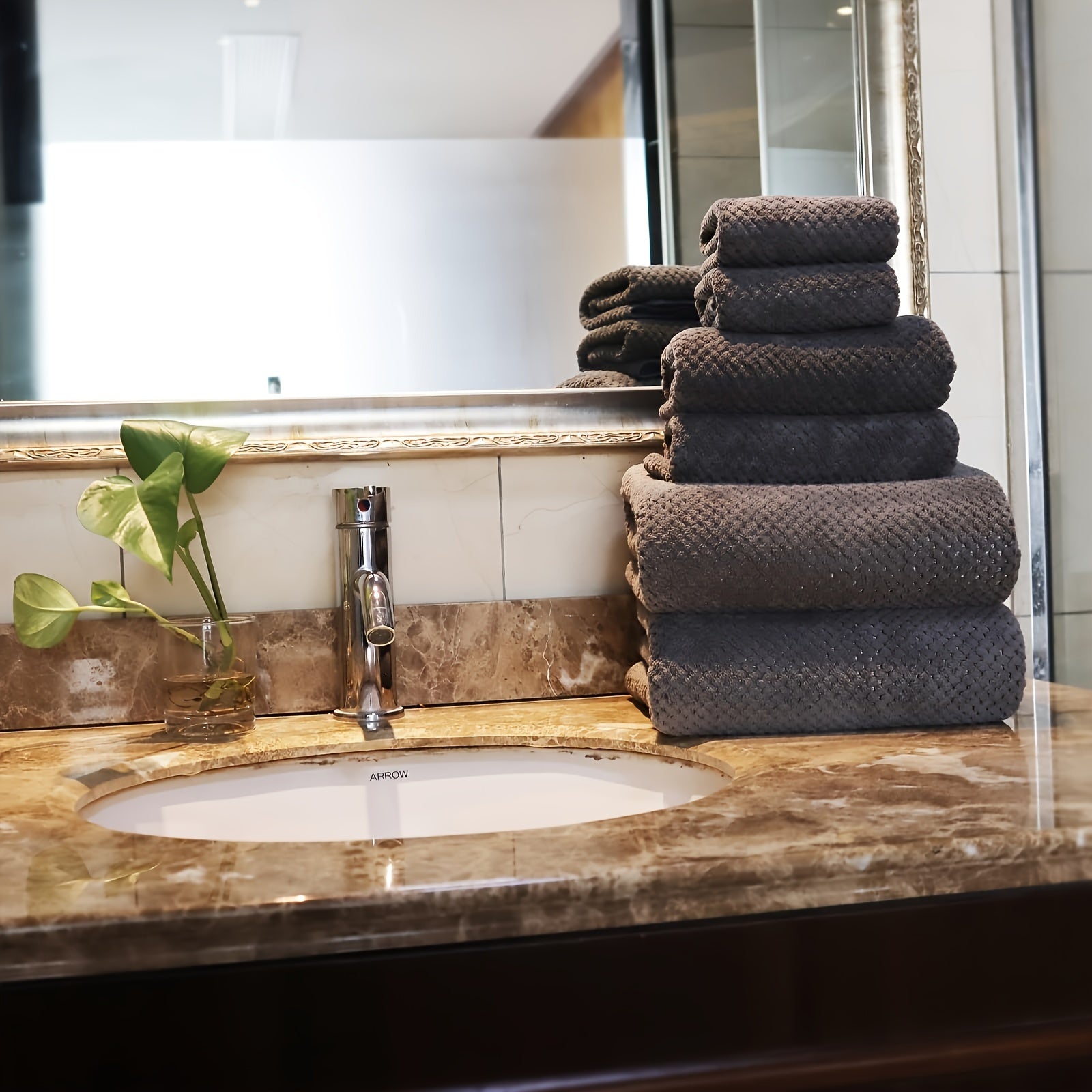 Luxury bath towel set neatly stacked on a marble countertop next to a sink in a modern bathroom