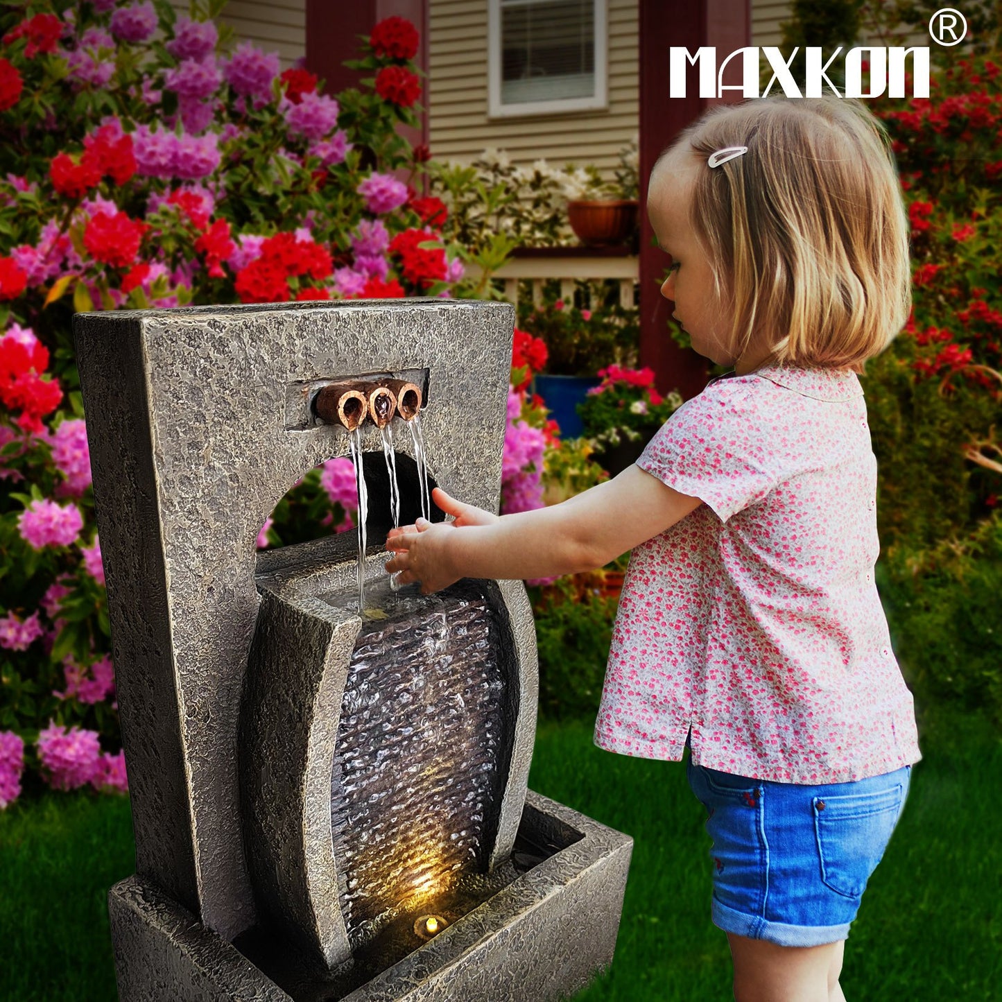 Child enjoying a solar waterfall fountain with a decorative stone design in a colorful garden