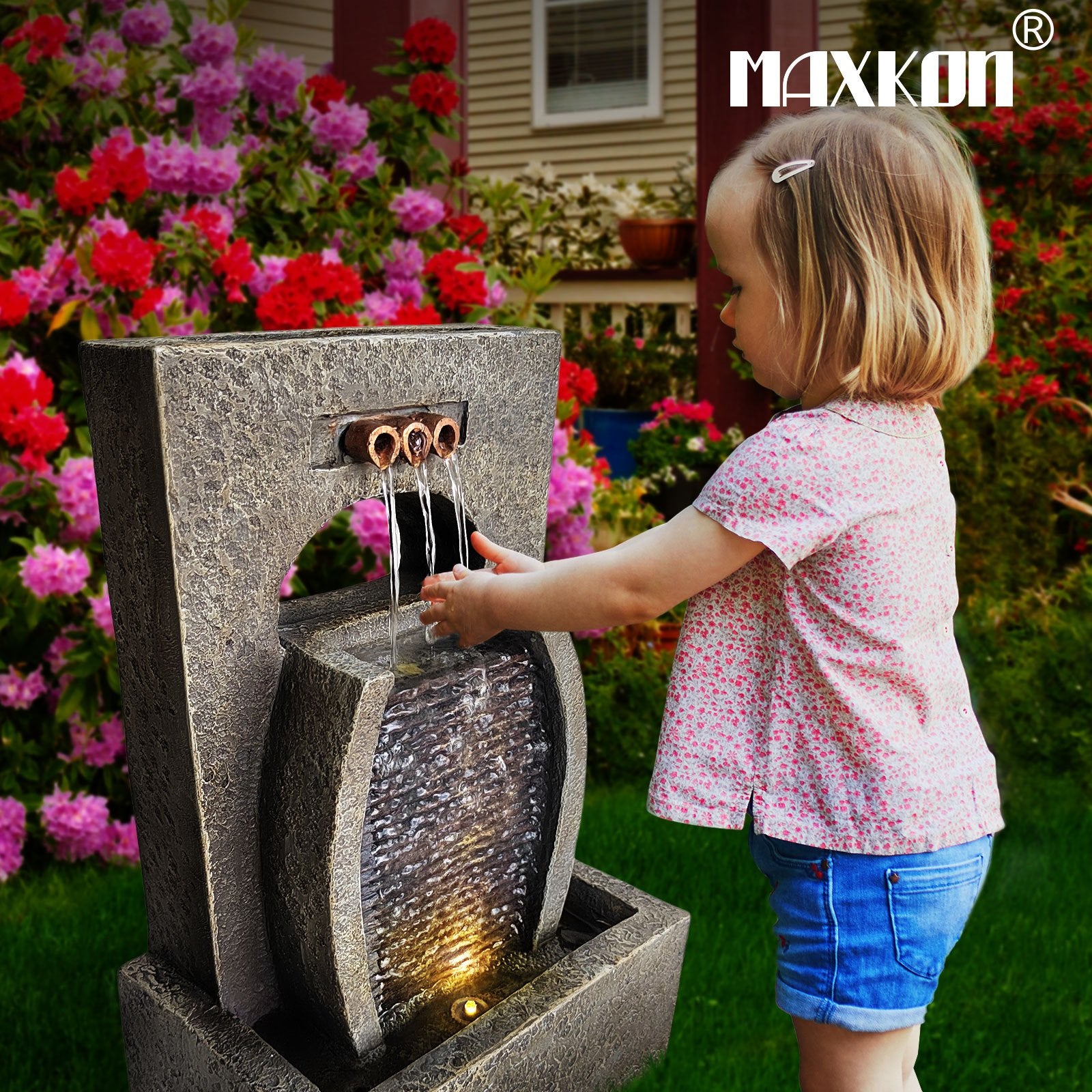 Child enjoying a solar waterfall fountain with a decorative stone design in a colorful garden