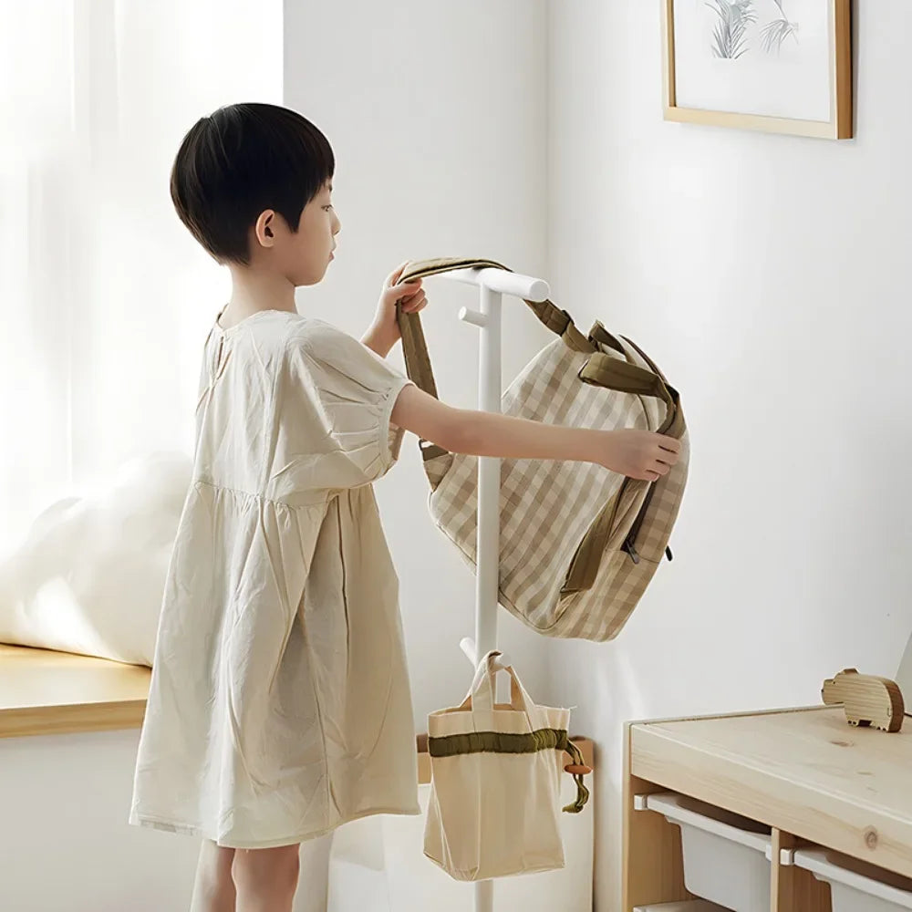 Nutshell coat stand used as School Bag Storage Rack with child hanging a backpack in a bright minimalist room