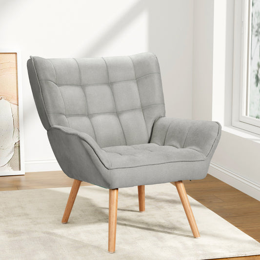 Nutshell Tufted Wingback Armchair in light gray fabric with wooden legs in modern living room