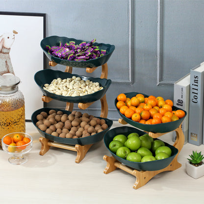 Nutshell multi-tier serving stand with green fruit bowls holding assorted nuts, candies, apples, and oranges