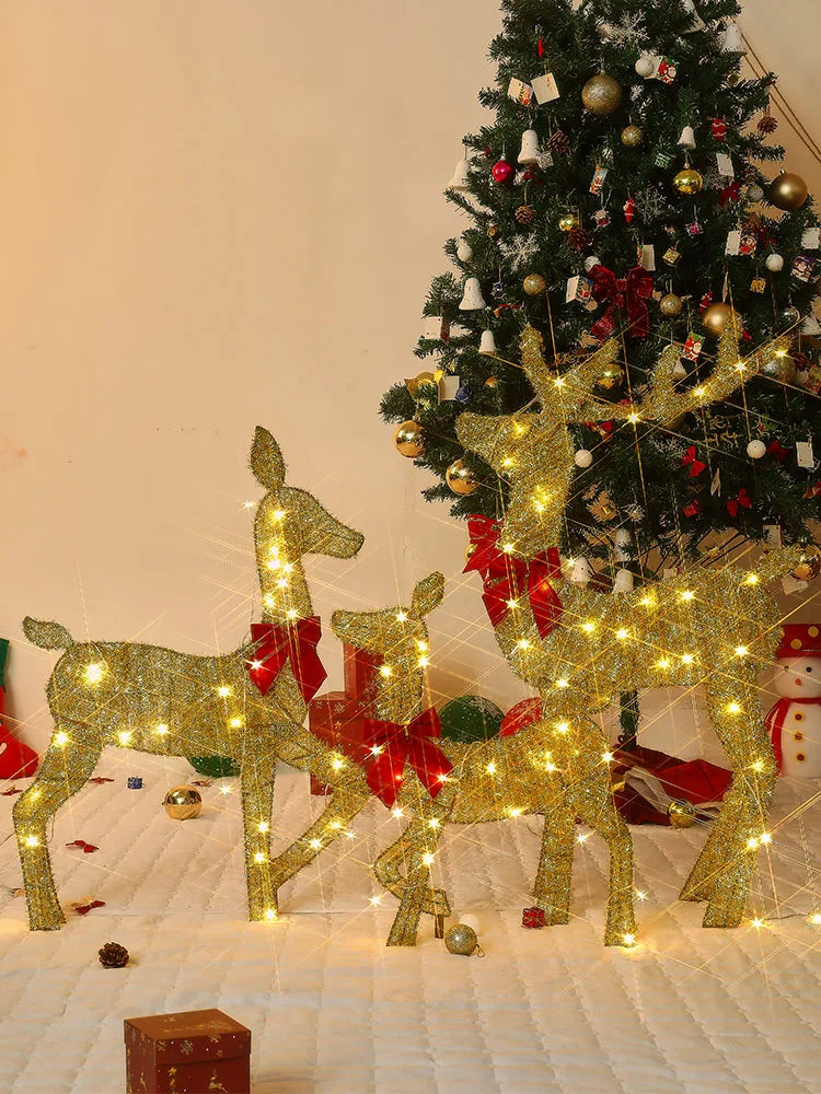 Glittering outdoor Christmas deer decorations with lights beside a beautifully decorated tree