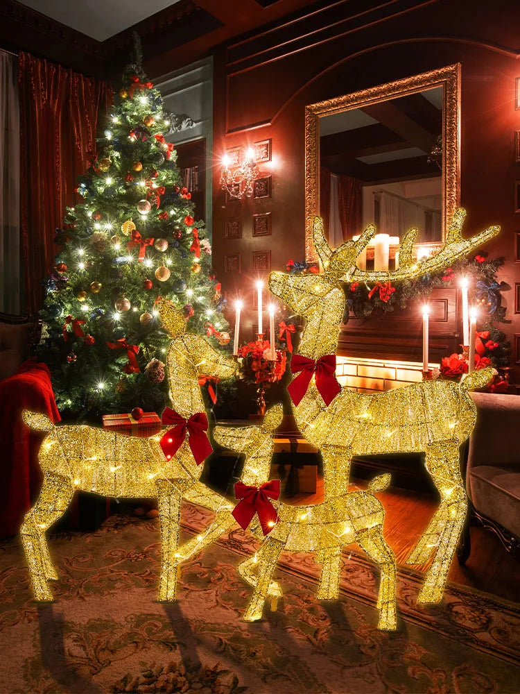Nutshell outdoor Christmas deer decorations in festive gold with red bows near a beautifully lit Christmas tree