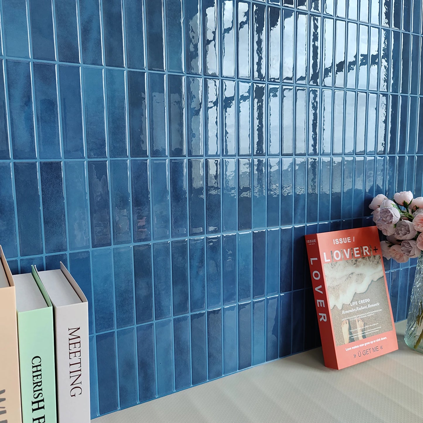 Nutshell glossy blue rectangular mosaic DIY Backsplash Tiles installed over desk with books and vase of flowers