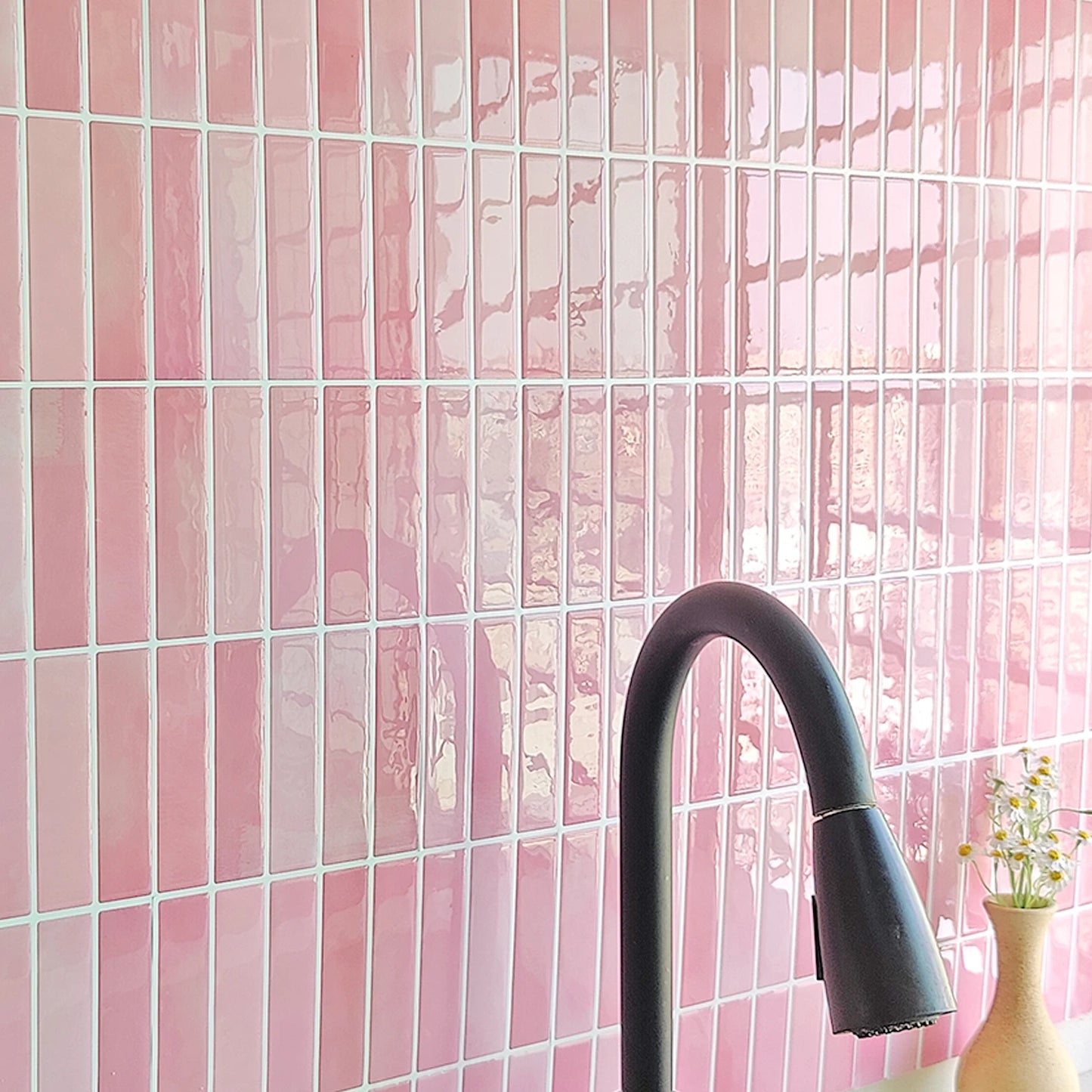 Nutshell pink glossy DIY Backsplash Tiles installed behind a black kitchen faucet and small vase