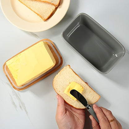 User spreading butter from a porcelain butter box with bamboo lid onto a slice of bread