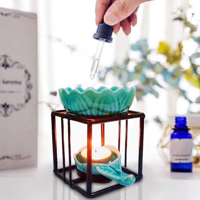 Porcelain lotus essential oil burner by Nutshell with teal ceramic lotus and black metal frame with lit candle