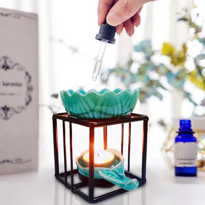Porcelain lotus essential oil burner by Nutshell with teal ceramic lotus and black metal frame with lit candle