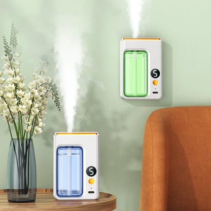 Nutshell portable diffuser emitting mist in green and blue colors on a wooden table and wall near a flower vase and orange chair