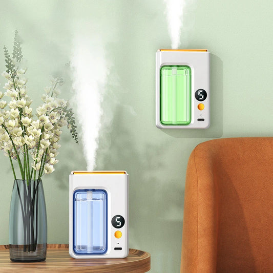 Nutshell portable diffuser emitting mist in green and blue colors on a wooden table and wall near a flower vase and orange chair