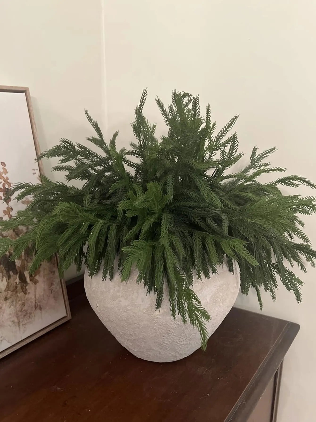 Decorative arrangement of real touch faux pine branches in a stylish white pot