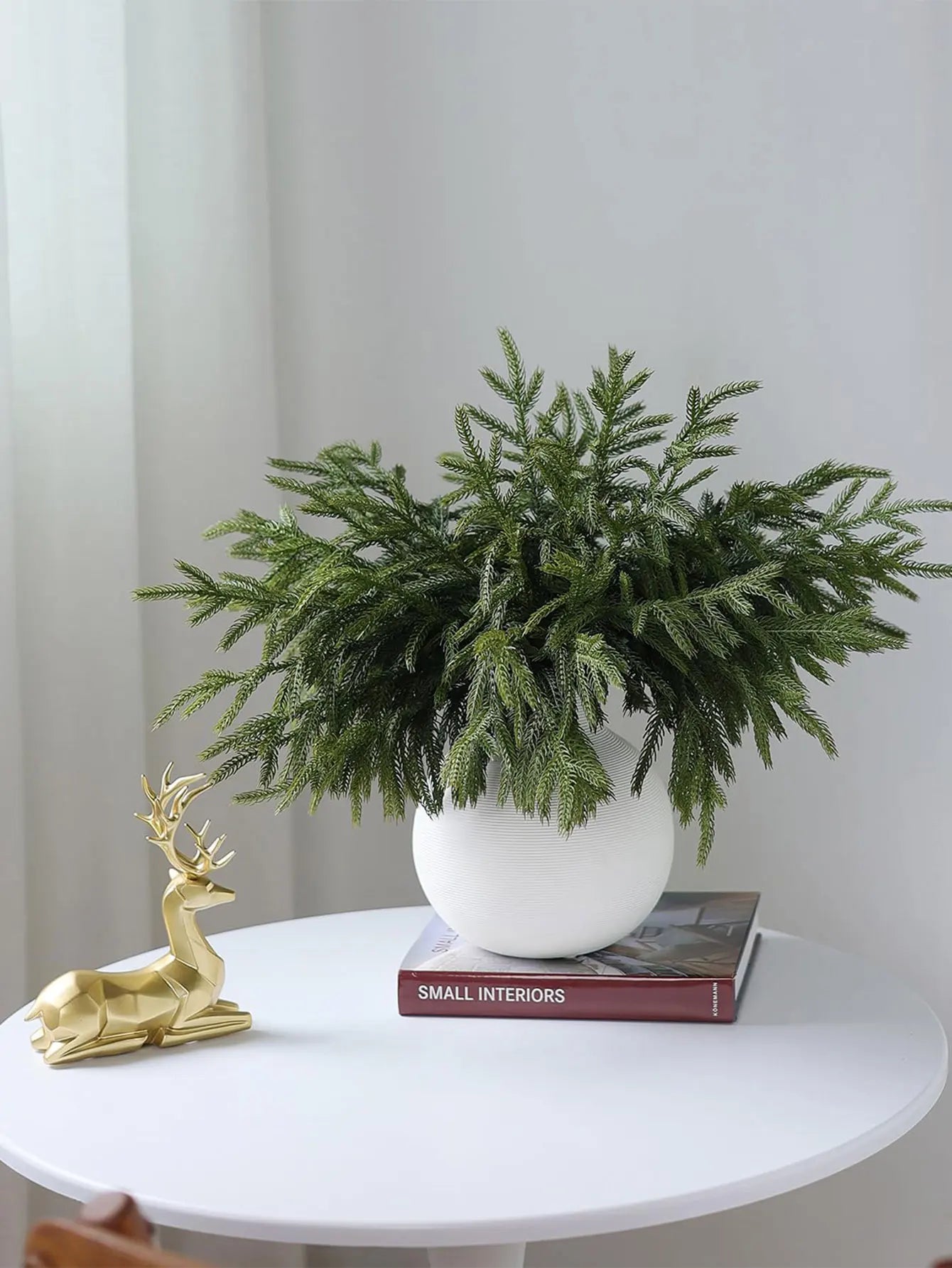 Elegant arrangement of real touch faux pine branches in a modern white pot on a table