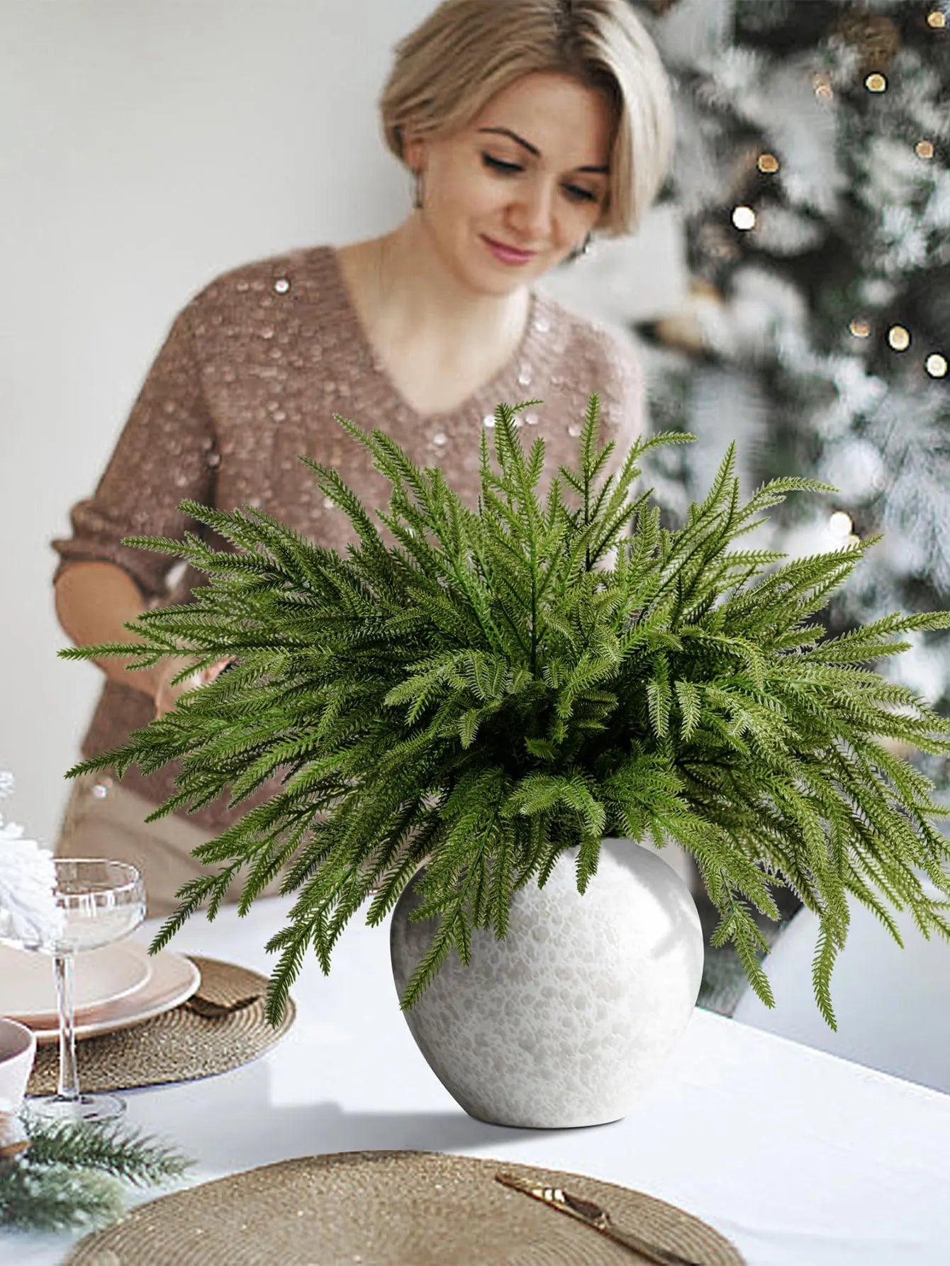 Elegant arrangement of real touch faux pine branches in a decorative vase on a festive dining table