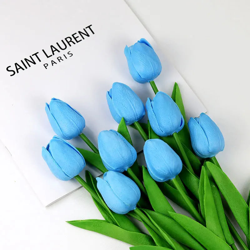 Realistic artificial tulip bouquet in blue with vibrant petals and lush green leaves.
