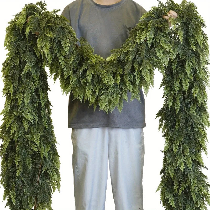 Person holding two strands of realistic Christmas garland made of lush green foliage