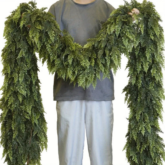 Person holding two strands of realistic Christmas garland made of lush green foliage