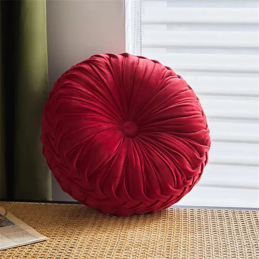 Nutshell red round pumpkin pillow cushion with soft pleated velvet fabric on a woven surface