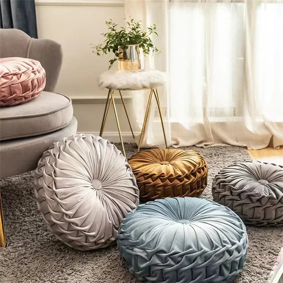 Nutshell round pumpkin pillow collection in various colors including pink, gray, blue, and gold on a living room carpet