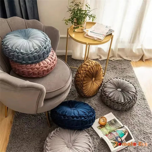 Nutshell round pumpkin pillow cushions in various colors arranged on chair and floor in cozy living room