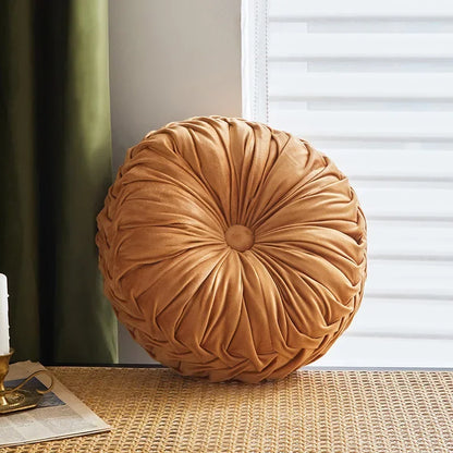 Nutshell round pumpkin pillow cushion in soft orange velvet texture on woven surface
