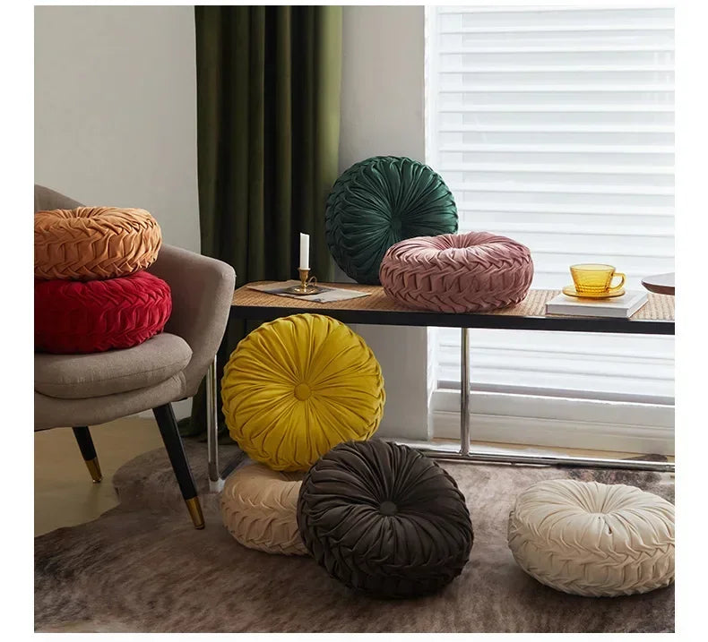 Nutshell round pumpkin pillow cushions in multiple colors displayed on chair, floor, and table