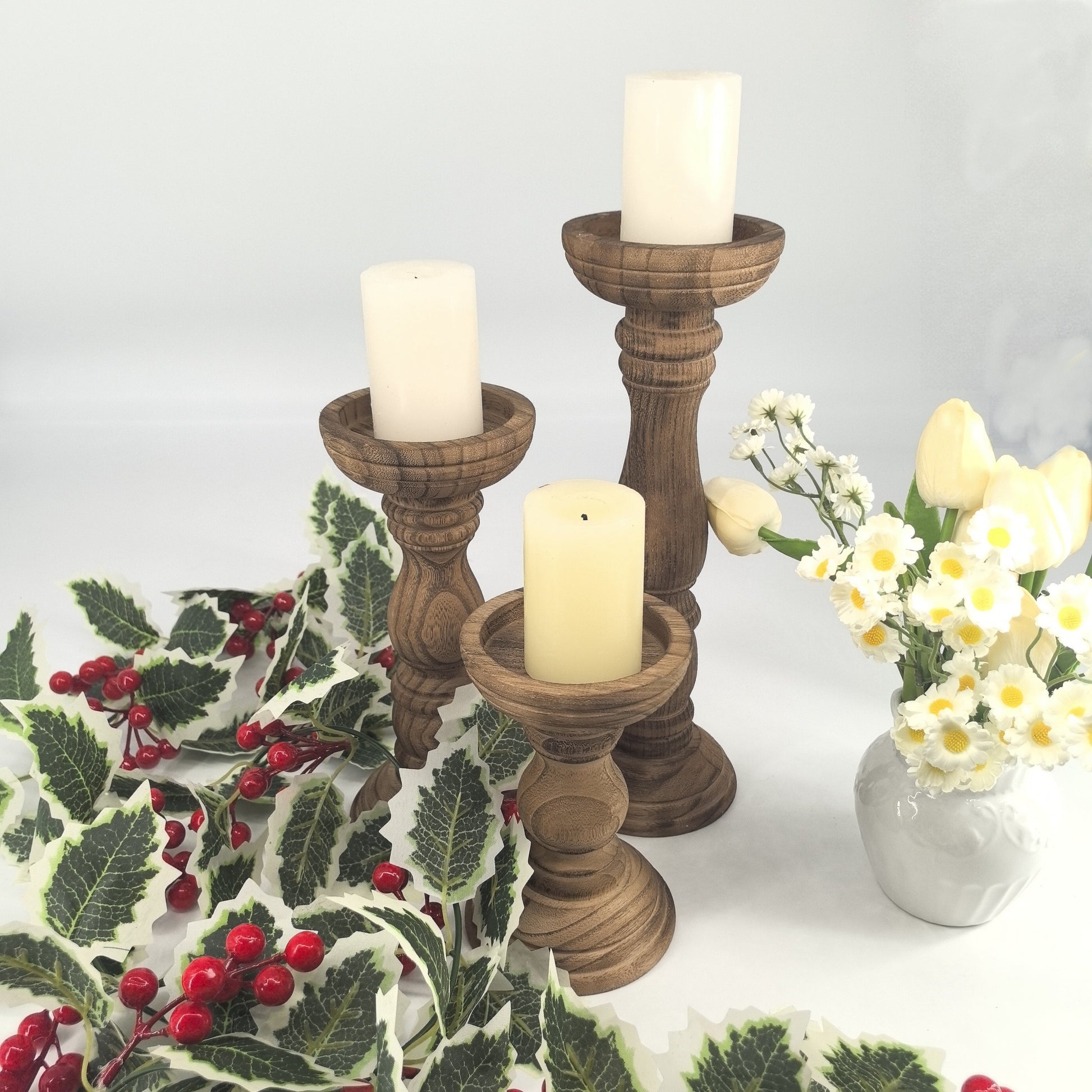Set of rustic farmhouse wooden candle holders in various heights with white candles and floral arrangement