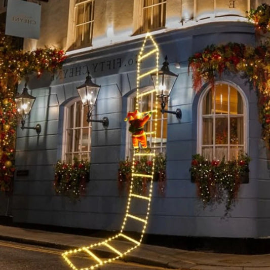 Santa climbing ladder Christmas decoration illuminated outside a festive building