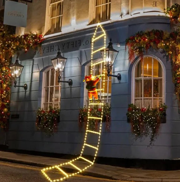 Santa climbing ladder Christmas decoration with lights displayed on a festive building exterior