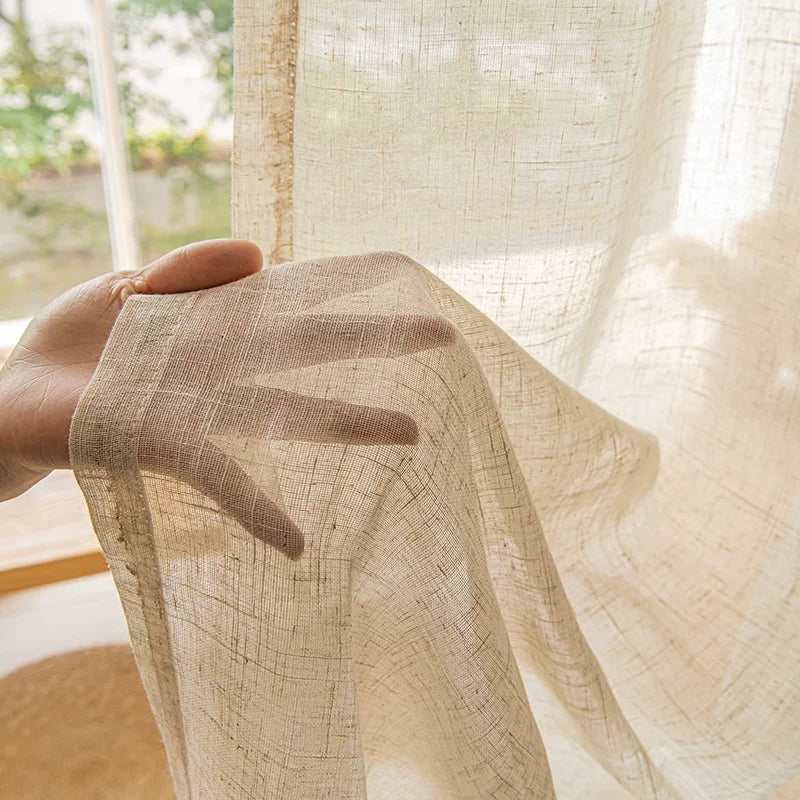 Nutshell Cotton Linen Beige Sheer Curtains lightweight semi transparent woven fabric shown with hand holding curtain by window
