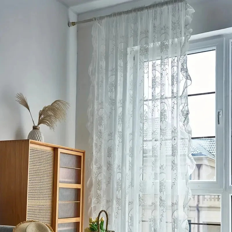 Nutshell Ruffled Floral Sheer Curtain in white hanging by window with ruffle trim and floral pattern