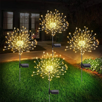 Set of solar firework garden lights illuminating a garden at night with bright golden lights
